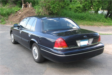 1999 Ford Crown Victoria - Rear three-quarter view of a dark blue Ford Crown Victoria sedan parked outdoors.