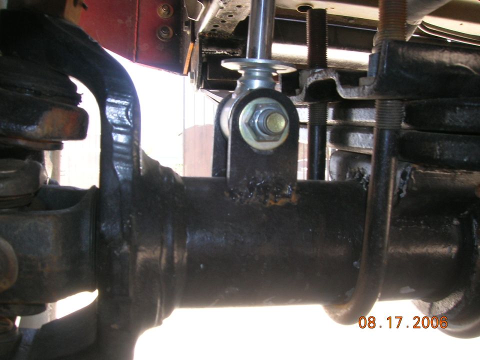 Underside close-up of shock mount with new bolt near leaf springs and U-bolts