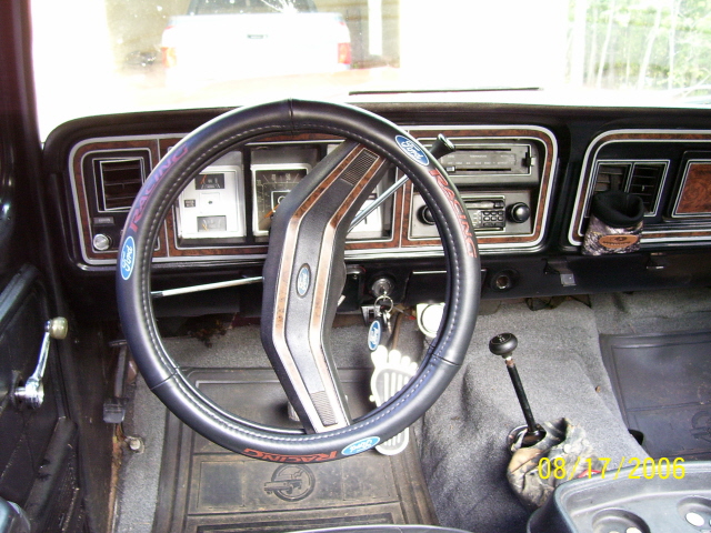 Interior shot of a truck's dashboard and steering wheel. Has a floor shifter and a radio