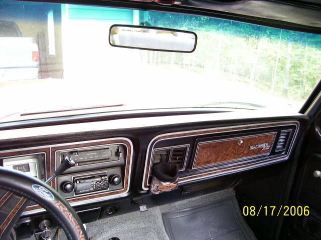 1979 Ford Bronco dashboard with wood grain trim, aftermarket radio, and Ford steering wheel
