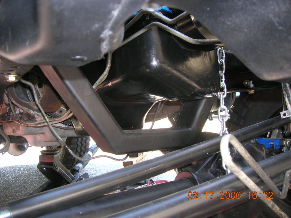 Undercarriage of a truck showing black fuel tank, skid plate, driveshaft and frame