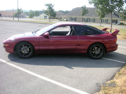 1993 Ford Probe - Side profile of a red 1993 Ford Probe GT parked in a lot on a sunny day.