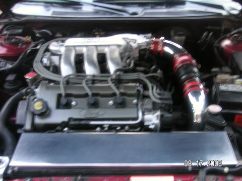 1993 Ford Probe - Engine bay of a 1993 Ford Probe, an aftermarket intake system and the Ford logo on the valve cover.