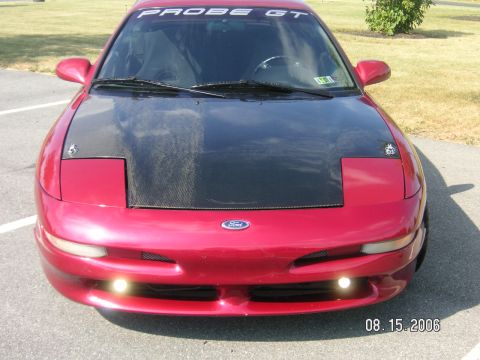 1993 Ford Probe - A red Ford Probe GT is shown from the front, a black hood and the 'PROBE GT' banner on the windshield.