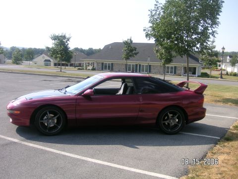 1993 Ford Probe - A red 1993 Ford Probe GT is parked in a lot, showing its side profile and rear spoiler.