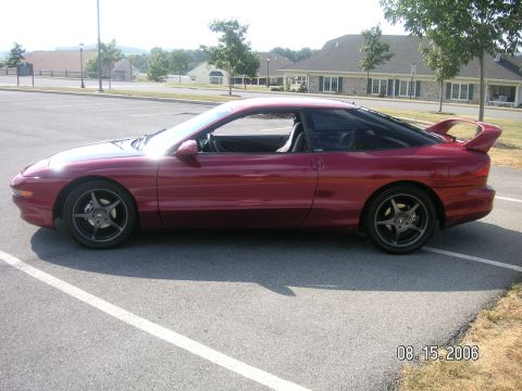 1993 Ford Probe - A red 1993 Ford Probe GT is parked in a lot, showing its side profile and rear spoiler.