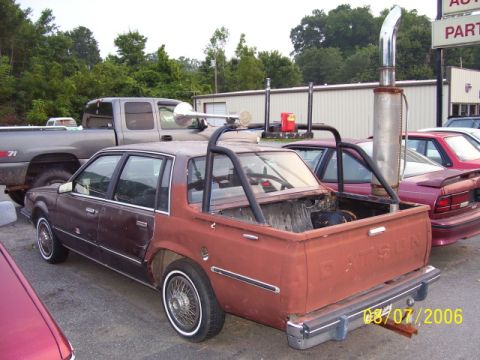 1979 Ford Bronco - Custom Datsun pickup truck with a large exhaust stack and roll cage is parked outdoors.