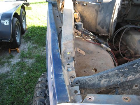 1977 Ford F-150 - Close-up view of a blue truck's fender and engine compartment, showing exposed wiring and mechanical parts.