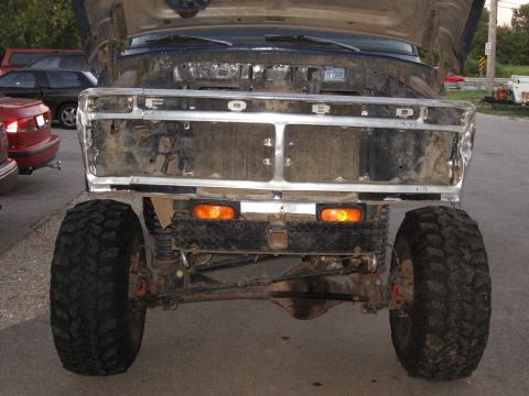 1977 Ford F-150 - This 1977 Ford F-150 is shown from the front with its hood up and grille missing, revealing its engine bay and off-road tires.