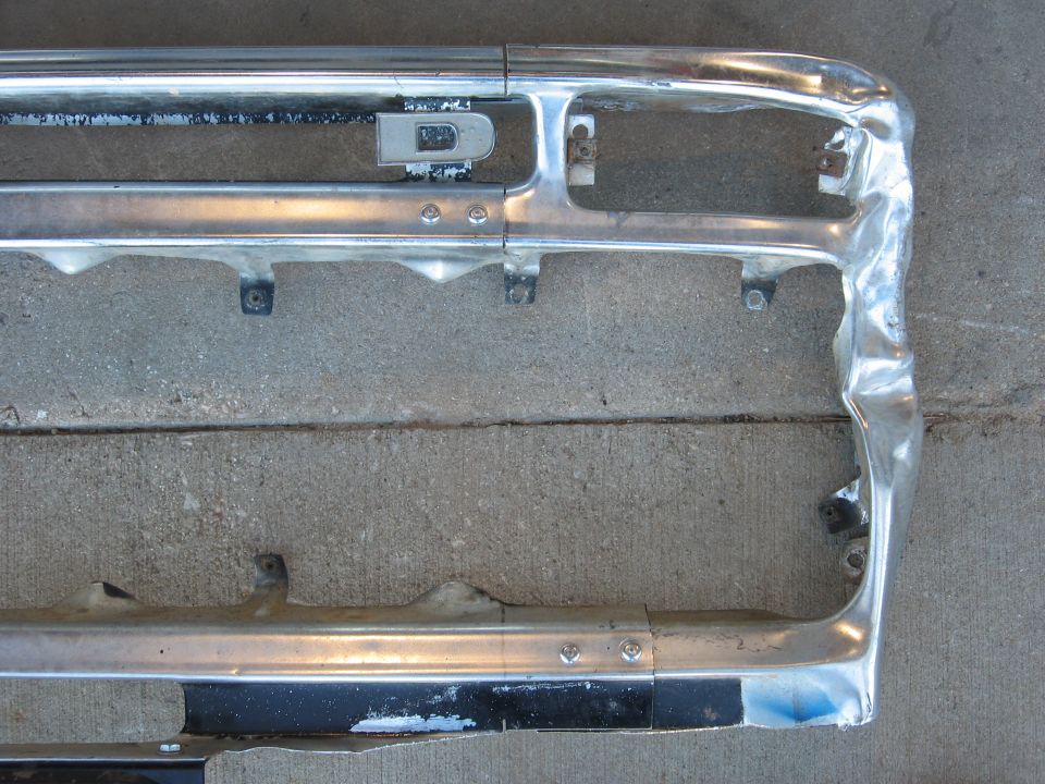 Chrome grille with horizontal bars and mounting points, dented on the right side