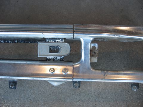 1977 Ford F-150 - Close-up of a chrome grille section a silver 'D' emblem, likely from an older vehicle.