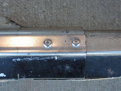 1977 Ford F-150 - Close-up of a chrome bumper section with visible rivets and some damage.