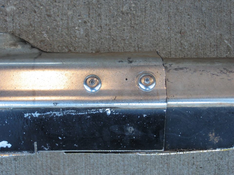 Chrome bumper section with two rivets visible, showing wear and tear