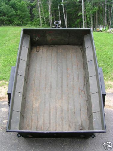 1991 Ford Bronco - The interior of a dark green trailer is shown from a high angle, with a wooded area visible behind it.