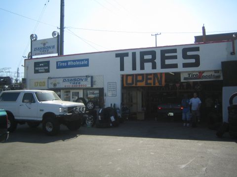 1990 Ford Bronco - tire shop with large TIRES and OPEN signage, a lifted white Ford Bronco parked at the curb out front.