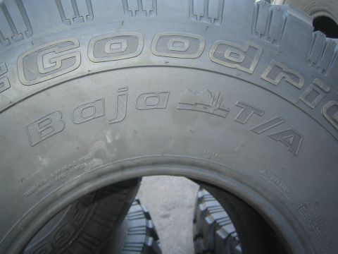 1990 Ford Bronco - Close-up of an off-road tire sidewall reading Goodrich Baja T/A, with aggressive tread blocks visible.