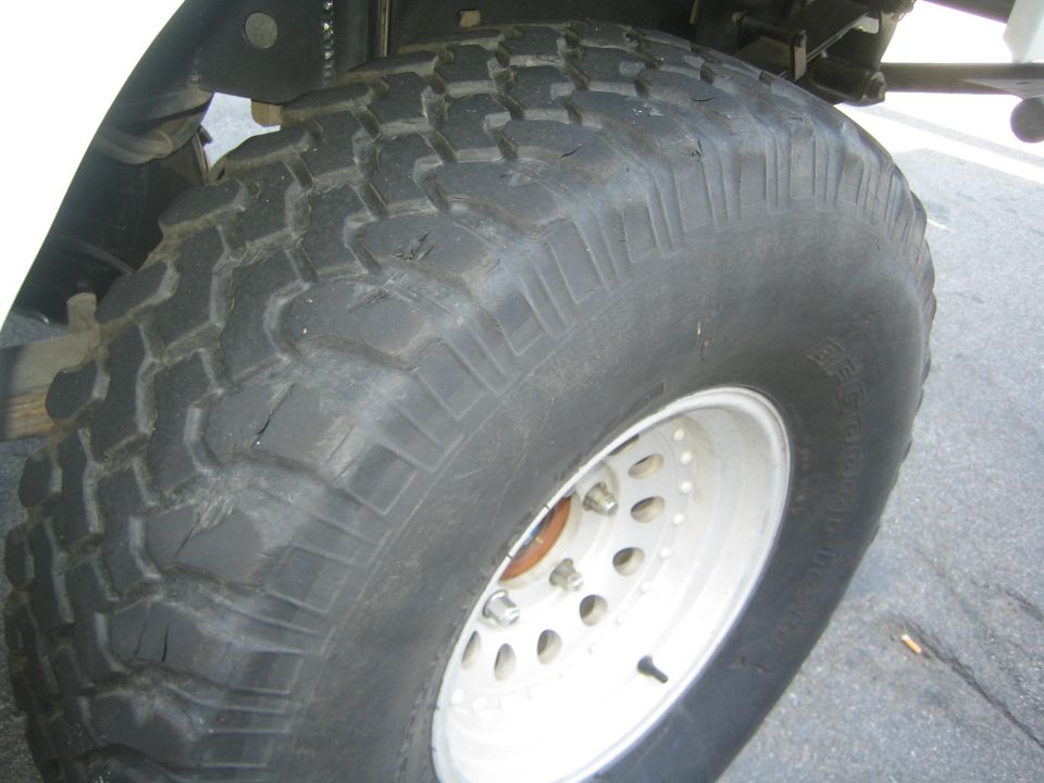 Mud-terrain tire on white steel wheel mounted under a vehicle fender