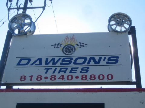 1990 Ford Bronco - outdoor Dawson's Tires shop sign topped with two chrome wheels, listing phone 818-840-8800.