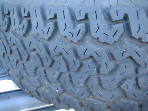 1990 Ford Bronco - extreme close-up of the worn, blocky aggressive tread pattern on the shoulder of a tire.