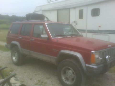 1992 Jeep Cherokee - This 1992 Jeep Cherokee features a roof rack with a cargo box, and a two-tone silver and red body.