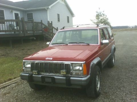 1992 Jeep Cherokee - A red Jeep Cherokee is parked in front of a house on a cloudy day.