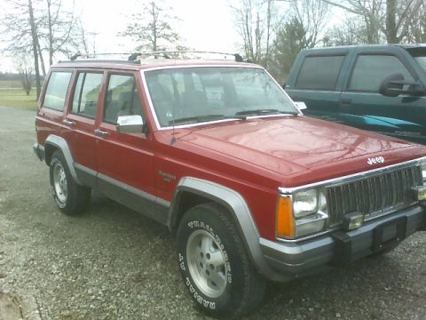 1992 Jeep Cherokee - Red 1992 Jeep Cherokee with roof rack parked outdoors next to a dark green truck.