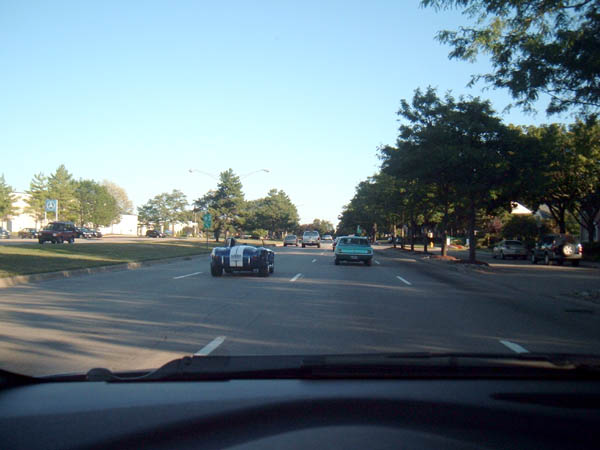 Blue and white striped sports car driving on a sunny day