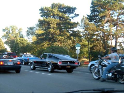 1971 Ford Ranchero - A black classic coupe is seen on the road alongside other vehicles and a motorcycle.