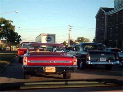 1971 Ford Ranchero - Two classic Chevrolet sedans, a red Bel Air and a dark model, are seen from behind in traffic.