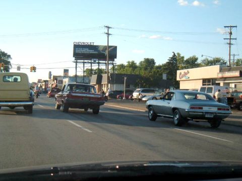 1971 Ford Ranchero - A silver 1969 Chevrolet Camaro drives down a street on a sunny day.