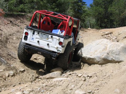 1996 Jeep Cherokee - This white Jeep Wrangler, equipped with a red roll cage and racing seats, tackles a challenging rocky off-road course.