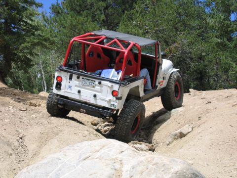 1996 Jeep Cherokee - A modified 1996 Jeep Cherokee navigates a challenging off-road course with its distinctive red roll cage and racing seats.