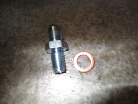 1994 Ford Bronco - A metal brake line fitting and a copper crush washer are shown on a shop floor.