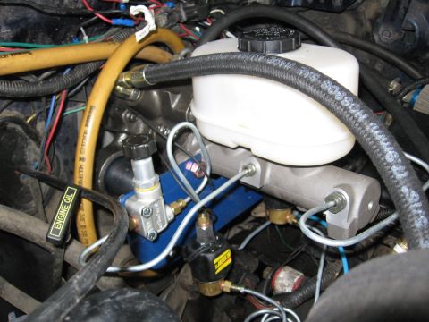 1994 Ford Bronco - Close-up view of the engine bay, focusing on the brake master cylinder and hydroboost system, with a yellow hose visible.