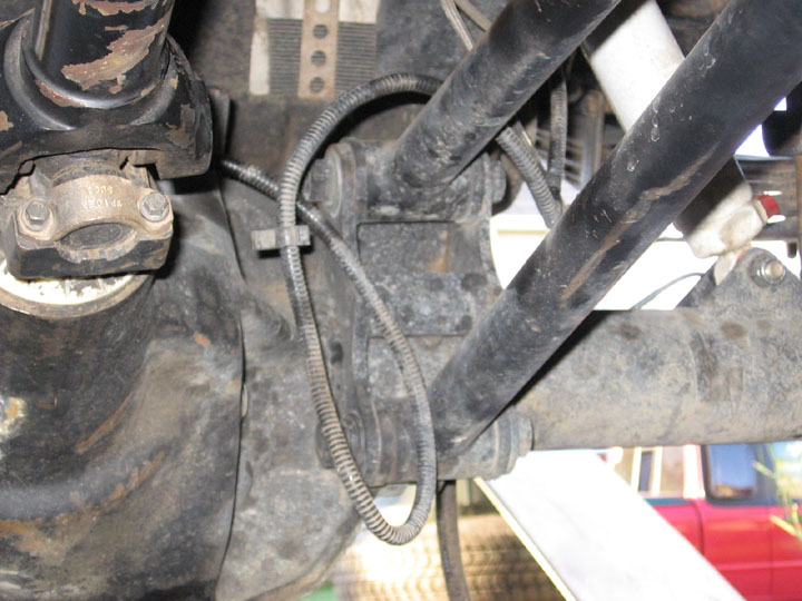 Underside close-up of rear axle pinion yoke with bolted torque arm bracket
