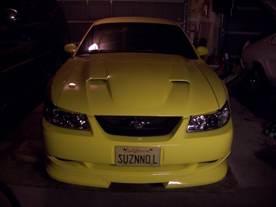 Yellow 2002 Ford Mustang front view in garage. California license plate reads SUZNNOL