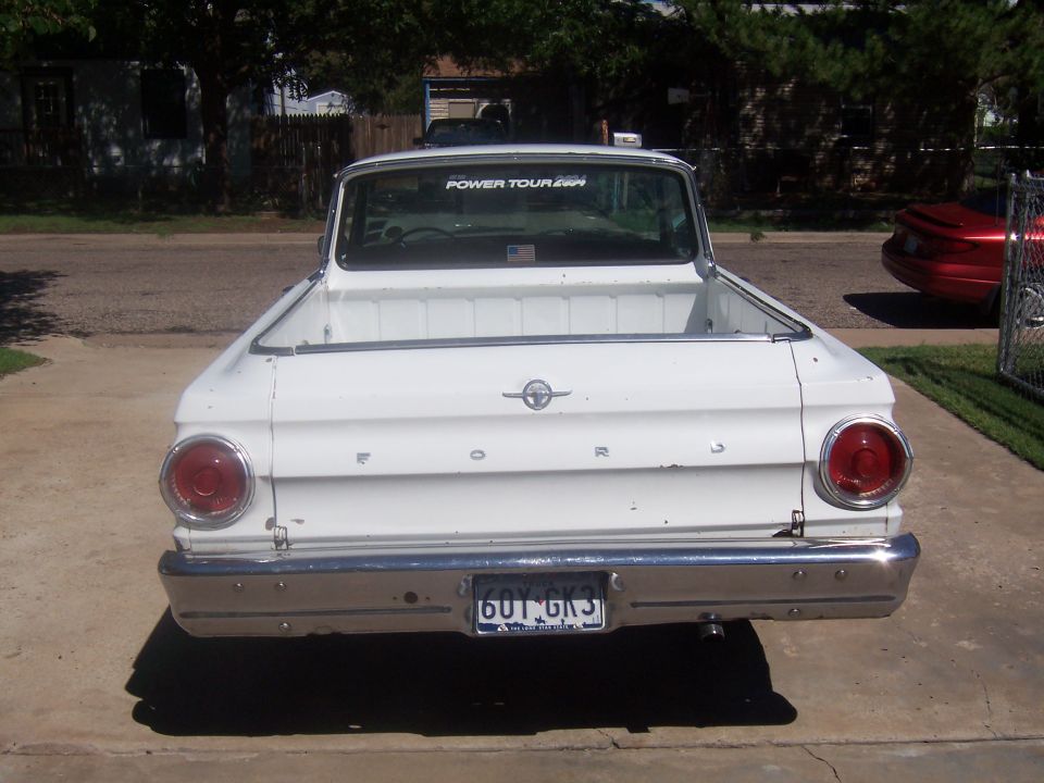 Rear view of a white 1964 Ford Ranchero with a chrome bumper and round taillights. License plate reads 601 GK3