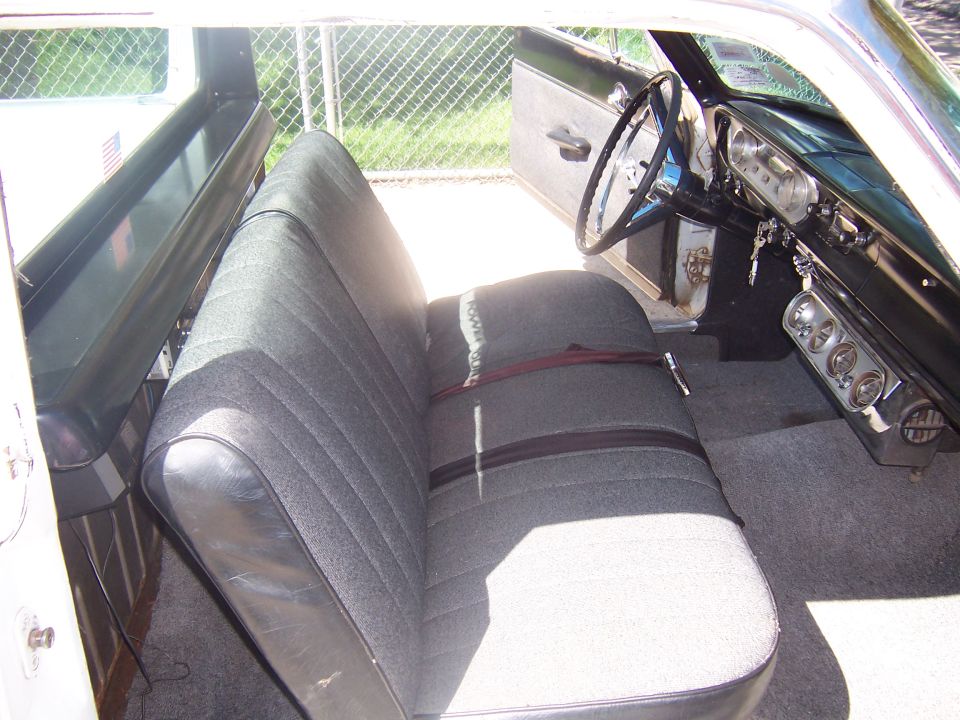 Interior shot of a car with bench seat, steering wheel, and dashboard gauges