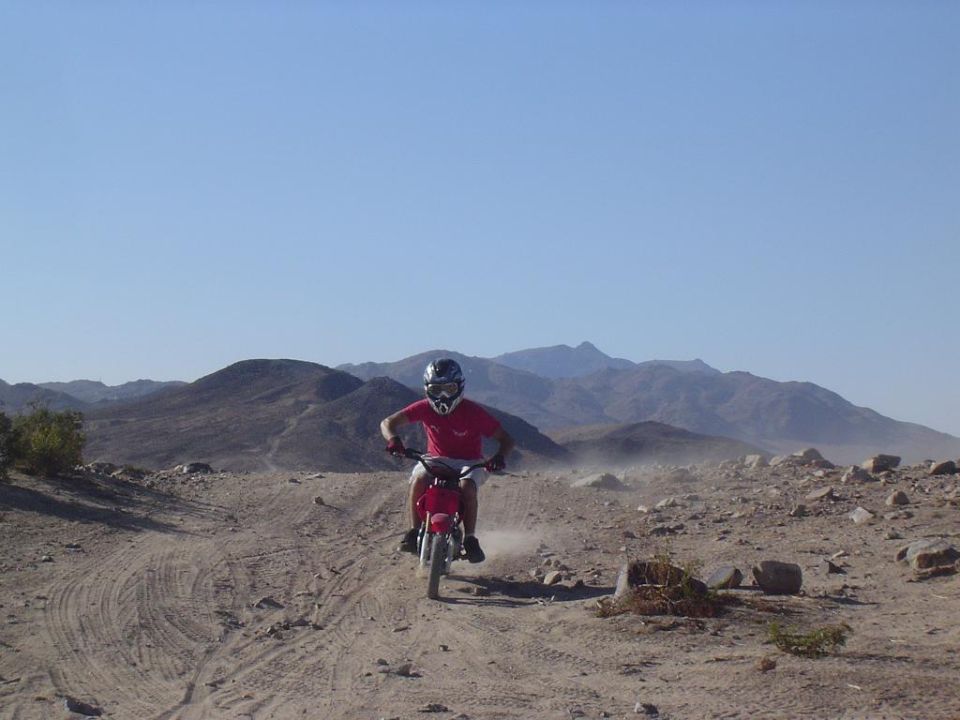 Red dirt bike with rider in desert landscape