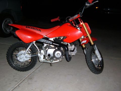 1985 Ford Bronco II - This red Honda dirt bike is parked on a concrete surface at night.