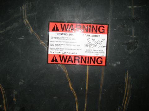 1993 Ford Bronco - A warning label is affixed to a dark surface, cautioning about rotating shafts and the need to read the PTO owners manual.