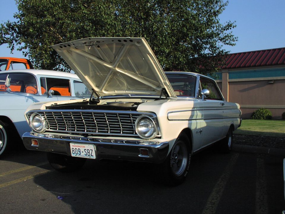 Cream 1963 Ford Falcon with hood open, parked next to other vehicles