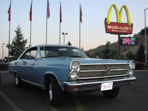 1979 Ford Bronco - A classic Ford Fairlane sits in a parking lot with flags and a McDonald's sign in the background.