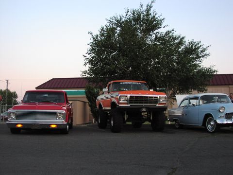 1979 Ford Bronco - Three classic vehicles are parked in a lot under a large tree.