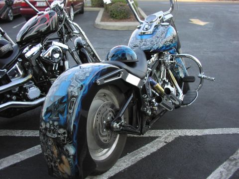 1979 Ford Bronco - Custom motorcycle with elaborate skull and flame paint job on the rear fender. Another bike is parked nearby.