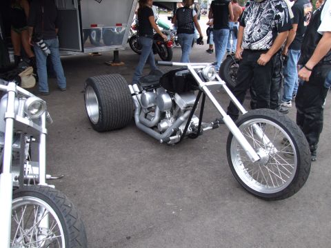 1997 Jeep TJ - A custom trike motorcycle with a massive rear tire and chrome accents is parked outdoors near other vehicles and people.