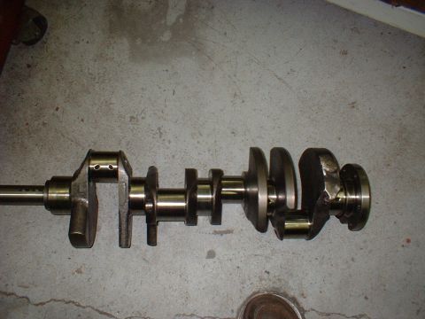 1967 Ford Fairlane - A crankshaft is shown resting on a concrete surface. This engine component is crucial for converting reciprocating motion into rotational m…