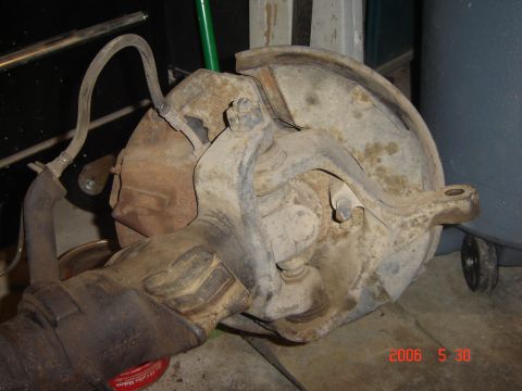 1993 Ford Bronco - Close-up view of a vehicle's front axle assembly, showing brake components and suspension linkage.