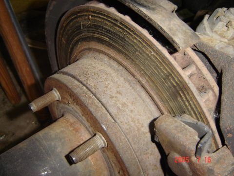 1993 Ford Bronco - Close-up of a rusted brake rotor and hub assembly, showing wear and two wheel studs.