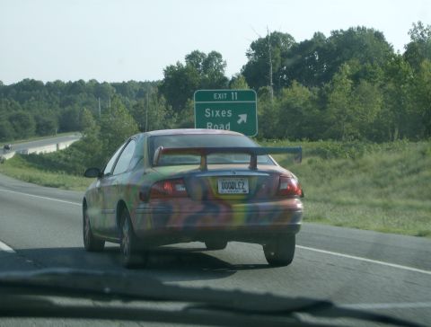 1998 Ford Taurus - A 1998 Ford Taurus with a custom paint job and spoiler drives on the highway near Exit 11.